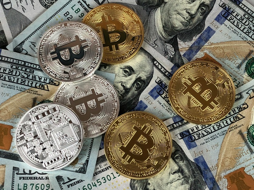 Bitcoin coins on US dollar bills, showing beginners that cryptocurrency is an alternative form of currency alongside traditional money.