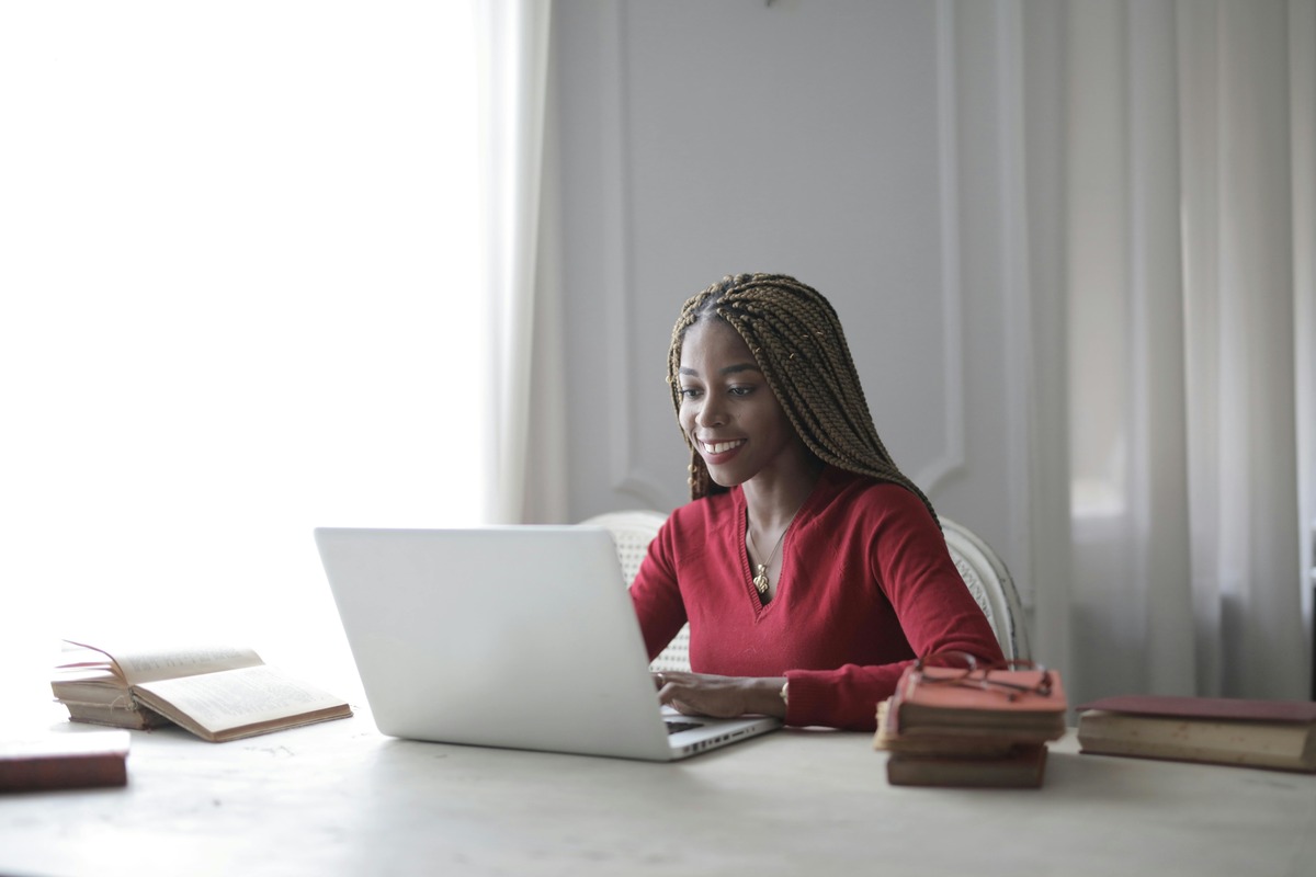 Crypto enthusiast sitting at a table with an open laptop in front of her, trying to figure out how to make money with cryptocurrency.